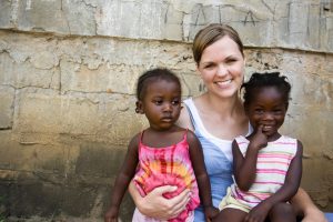 An American woman holding two African girls.