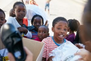 Cropped shot of volunteer workers handing out clothing to underprivileged children