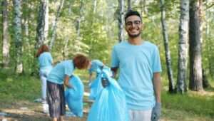 Volontärer samlar skräp i en skog med blå sopsäckar